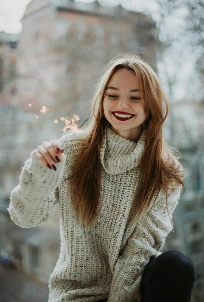 pexels-photo-789304-789304 Woman in cozy sweater smiling with a sparkler. Bright and happy indoor scene.